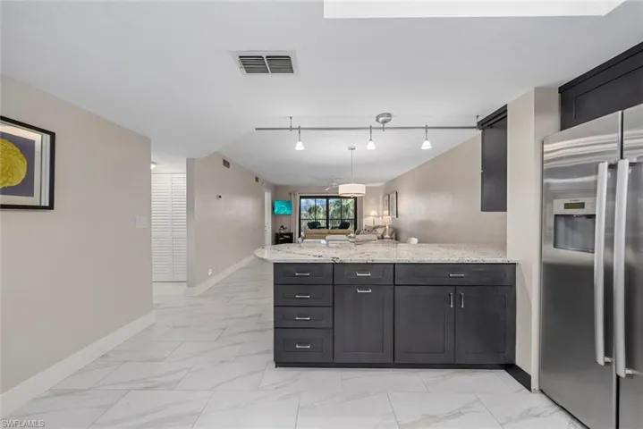 Kitchen island featuring dark wood cabinetry, a light-toned countertop, and stainless steel appliances