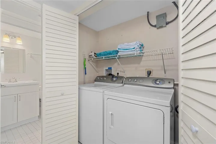 Dedicated laundry area featuring a full-sized washer and dryer, wire shelving, and a louvered bi-fold door