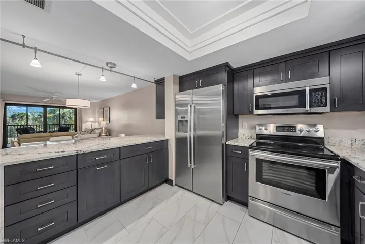 Modern kitchen featuring dark wood cabinetry, light-toned countertops, and stainless steel appliances