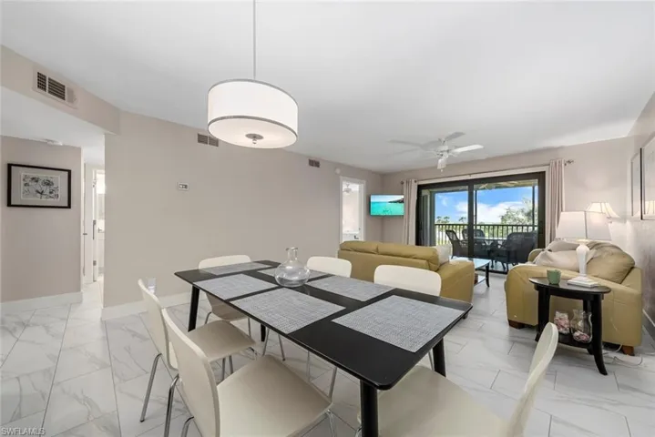 Open-concept living and dining area featuring large format tile flooring, a contemporary drum chandelier, and sliding glass doors leading to an outdoor space