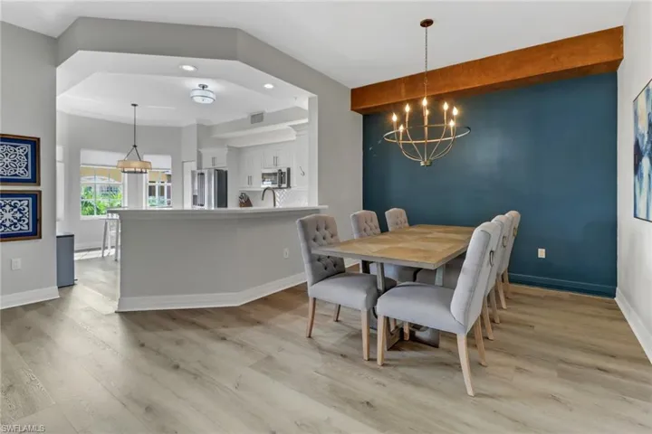 Dining space with light wood finished floors, and a notable chandelier