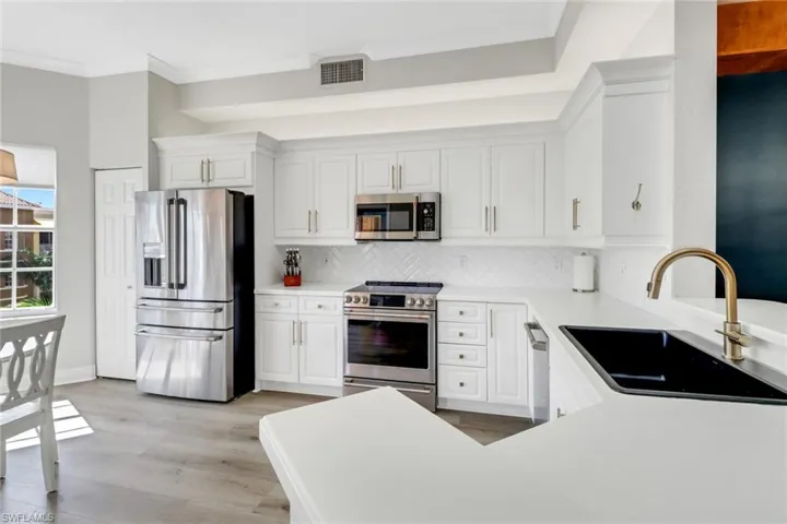 Kitchen featuring white cabinetry, appliances with stainless steel finishes, and backsplash