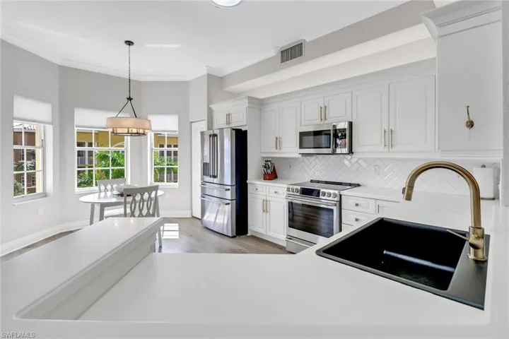 Kitchen featuring appliances with stainless steel finishes, a sink, light wood-style floors, decorative backsplash
