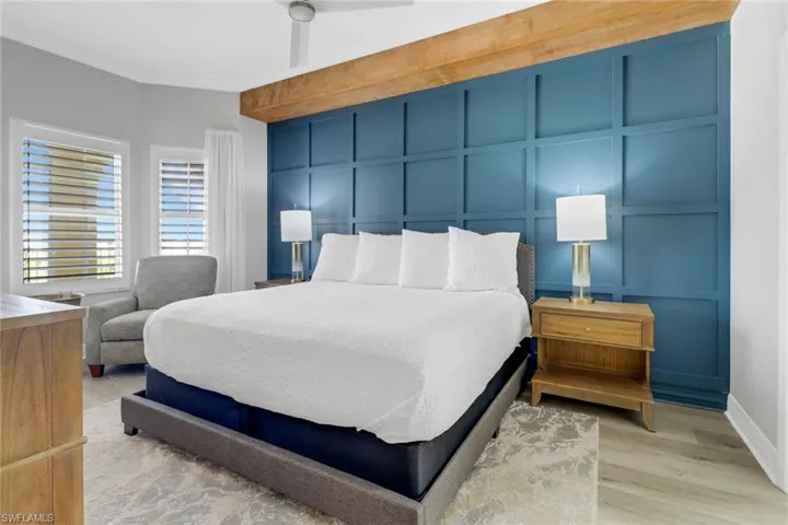 Bedroom featuring light wood-style floors, baseboards, and a decorative wall
