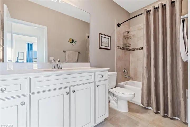 Guest bathroom with tile patterned flooring, vanity, toilet, and shower / tub combo