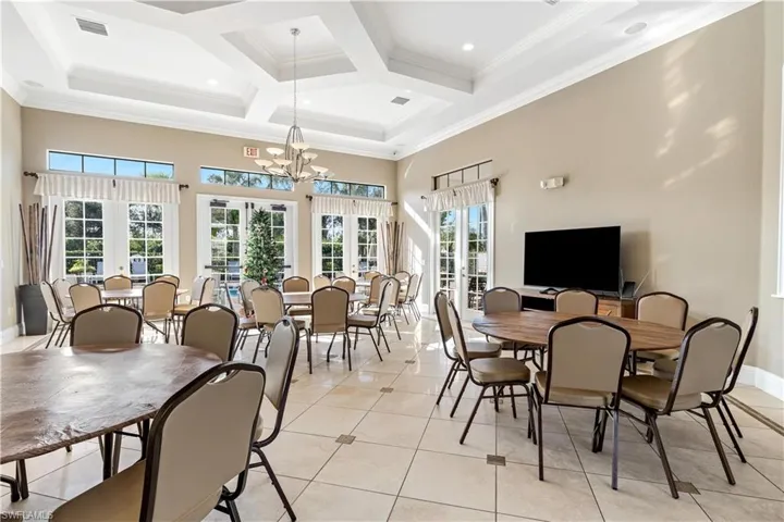 Tiled dining space featuring beam ceiling, french doors, coffered ceiling, a notable chandelier, and crown molding