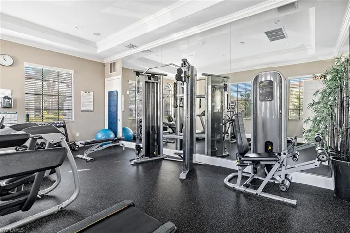 Workout area with a tray ceiling and ornamental molding