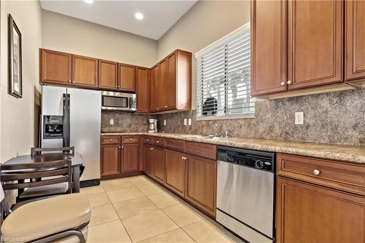 Kitchen with decorative backsplash, appliances with stainless steel finishes, light tile patterned flooring, and sink