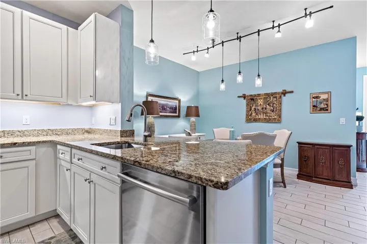Kitchen with kitchen peninsula, sink, white cabinets, and pendant lighting