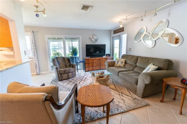 Open concept living room with designer lighting.  Impact windows and sliders guide out to the clean, tiled lanai.