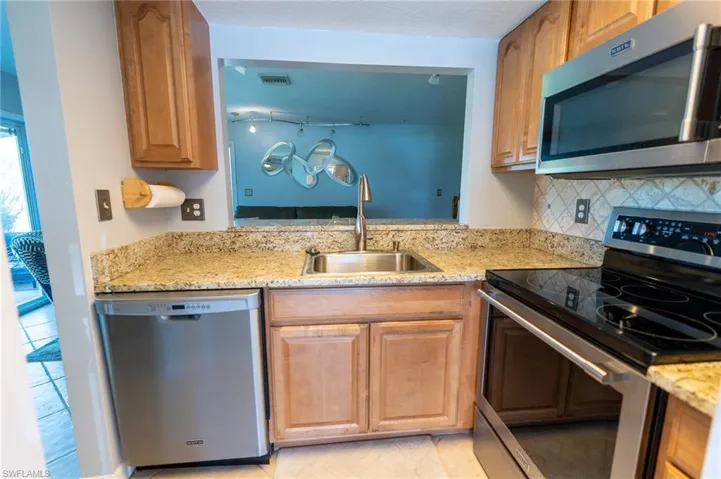Kitchen with stainless steel appliances and enlarged pass-through to living room.