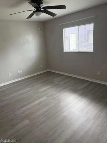 Spare room with dark wood finished floors and ceiling fan