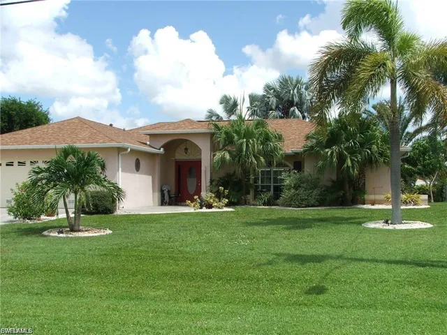 Mediterranean / spanish house with a garage, a front lawn, stucco siding, a shingled roof, and concrete driveway
