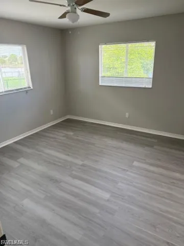 Unfurnished room featuring plenty of natural light, light wood-type flooring, and ceiling fan