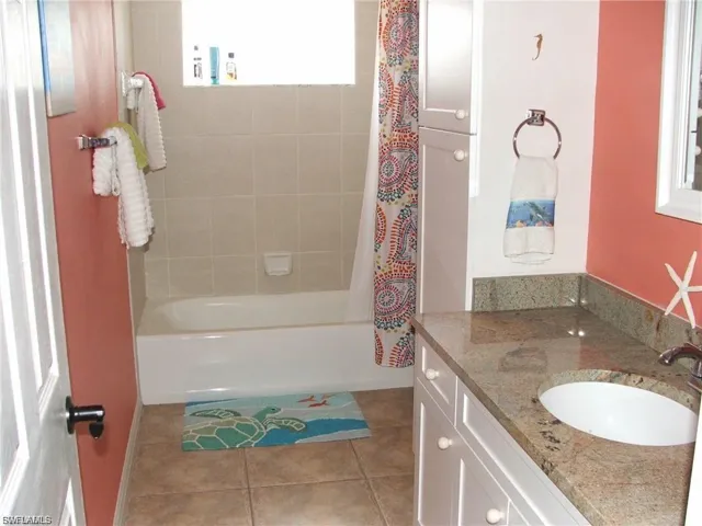 Full bathroom with vanity, shower / bathtub combination with curtain, healthy amount of natural light, and light tile patterned floors