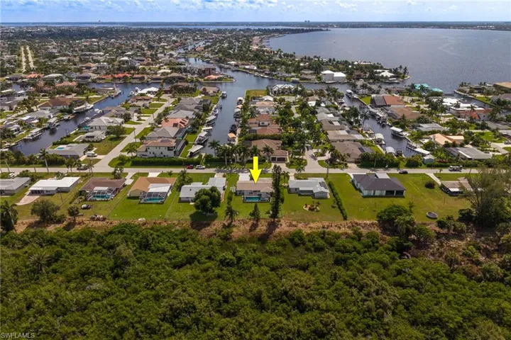 Aerial perspective showcasing a residential area with canal access, waterfront properties, and a large body of water in the background