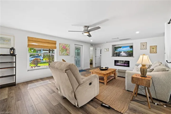 Wood-finish flooring, recessed lighting, and a ceiling fan enhance this living space