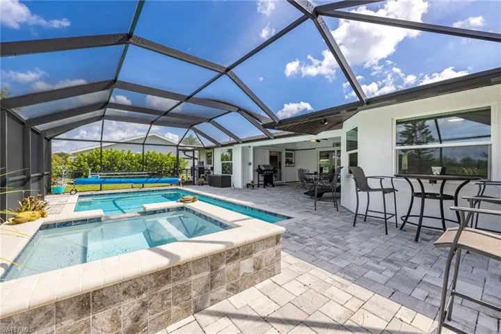 Screened outdoor living space featuring a pool, spa, and paver patio