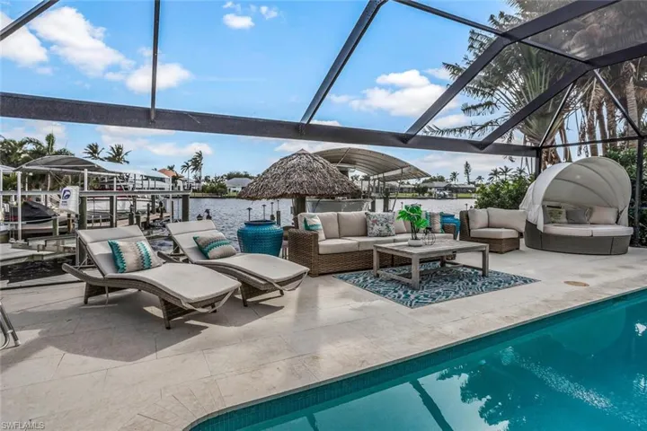 View of pool featuring an outdoor living space, a water view, glass enclosure, and a patio area