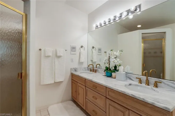 Bathroom featuring tile patterned flooring, vanity, and walk in shower