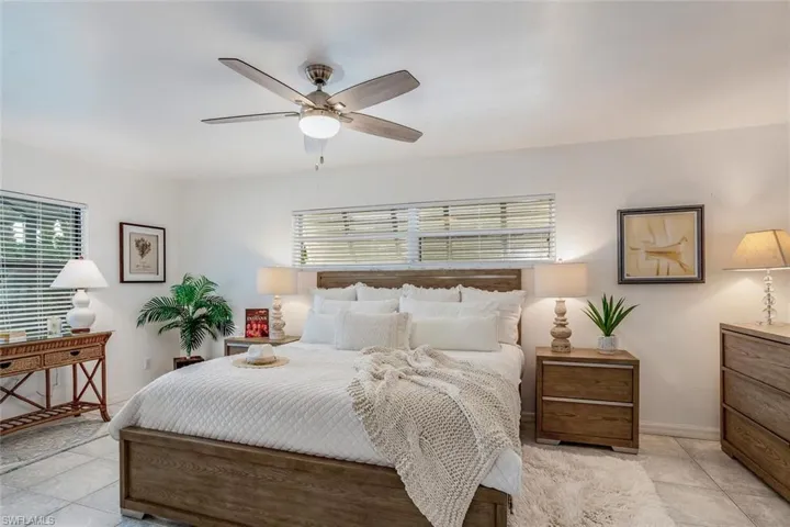 Bedroom featuring ceiling fan, light tile patterned floors, and multiple windows