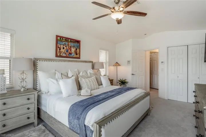 Carpeted bedroom featuring ceiling fan, lofted ceiling, and a closet