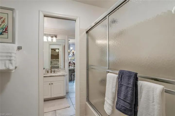 Bathroom featuring tile patterned flooring, vanity, and bath / shower combo with glass door