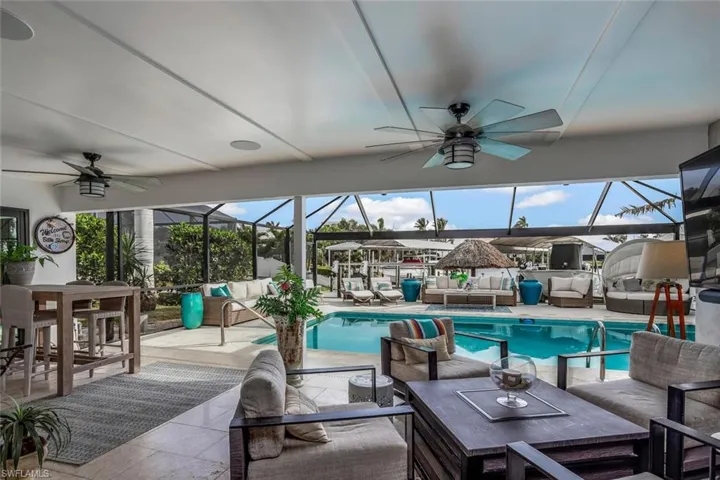 View of pool with a lanai, a patio area, ceiling fan, and an outdoor hangout area