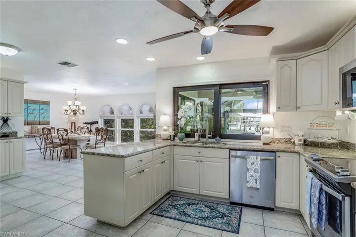 Kitchen featuring sink, light tile patterned floors, kitchen peninsula, white cabinets, and appliances with stainless steel finishes