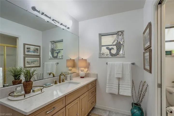 Bathroom with tile patterned flooring, vanity, a shower with door, and toilet