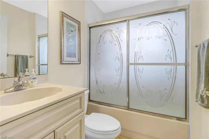 Full bathroom with vanity, shower / bath combination with glass door, and toilet