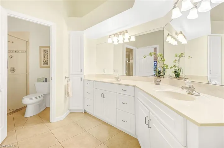 Bathroom with vanity, tile patterned floors, toilet, and an enclosed shower