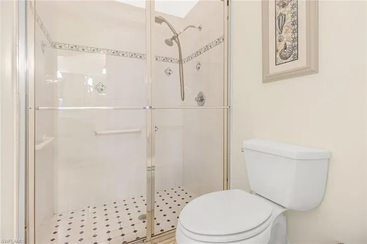 Bathroom featuring a shower with door and toilet