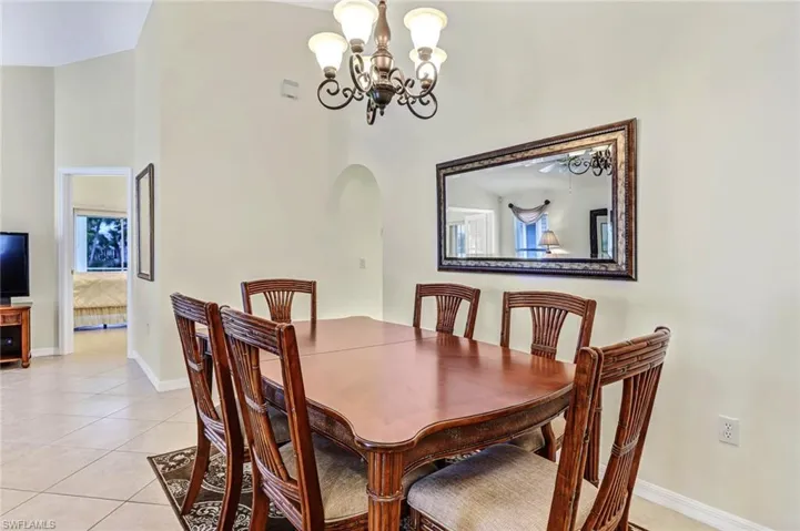 Dining space featuring ceiling fan with notable chandelier and light tile patterned floors
