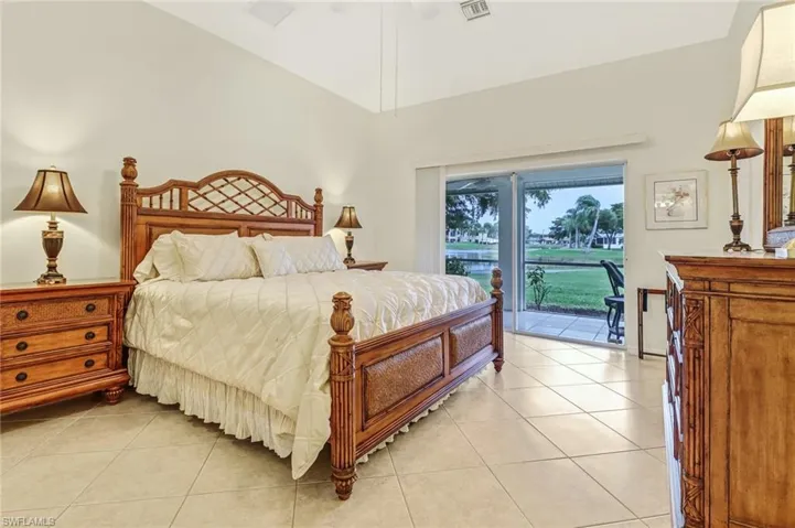 Tiled bedroom with ceiling fan, vaulted ceiling, and access to exterior