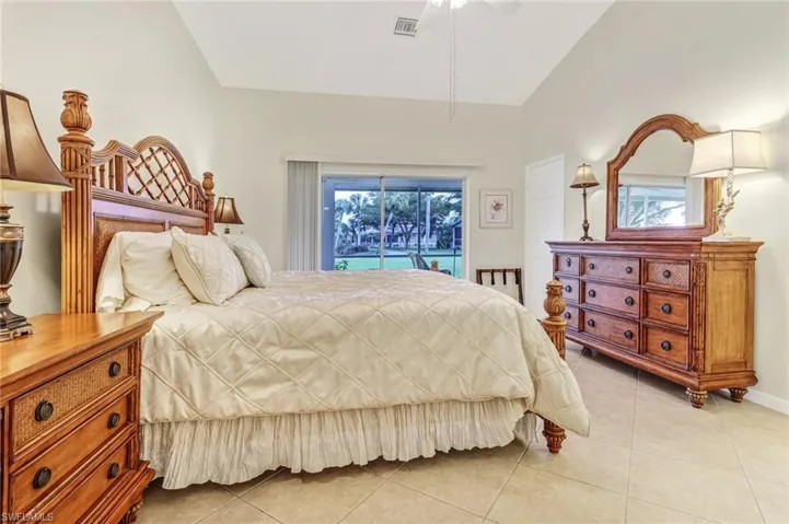 Tiled bedroom featuring vaulted ceiling, access to exterior, and ceiling fan