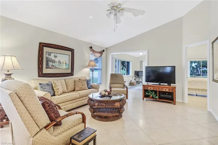 Tiled living room featuring ceiling fan, a healthy amount of sunlight, and vaulted ceiling