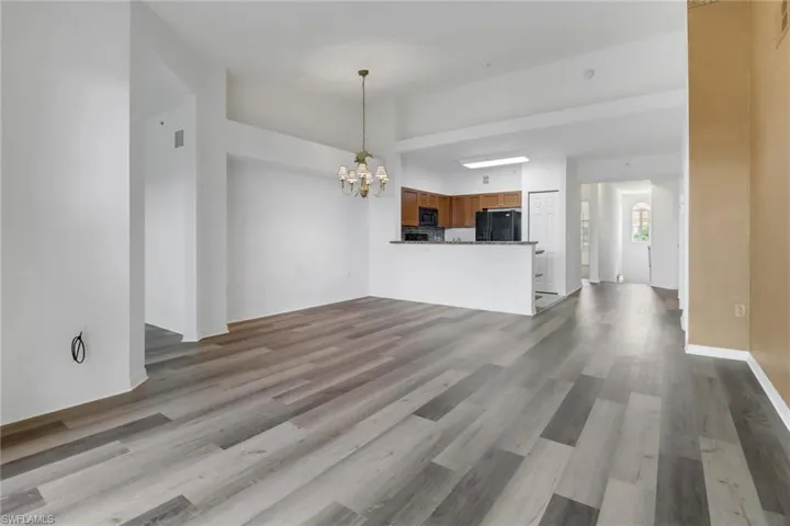 Unfurnished living room featuring light hardwood / wood-style floors and a notable chandelier