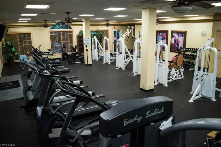 Exercise room featuring ceiling fan and a drop ceiling
