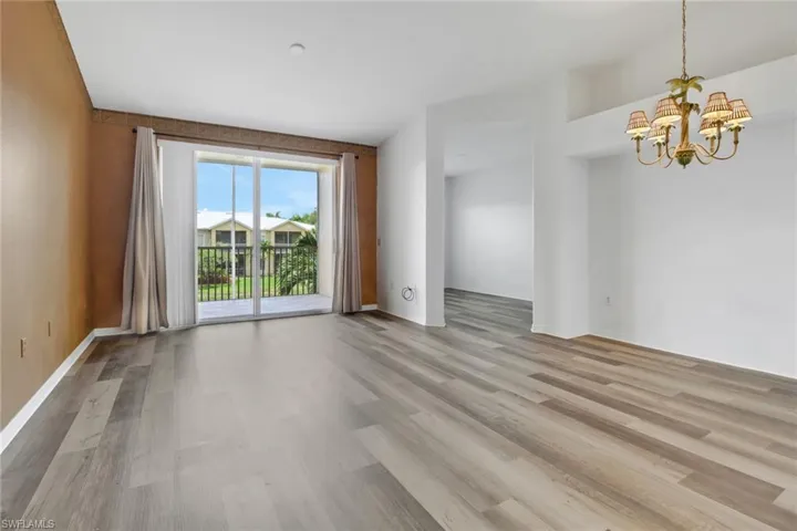 Spare room featuring a notable chandelier and light wood-type flooring