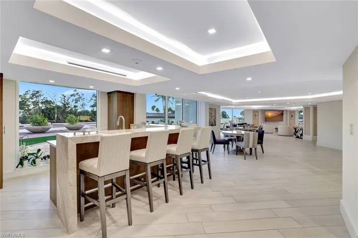 Kitchen with light stone counters, open floor plan, a breakfast bar area, recessed lighting, and a large island with sink