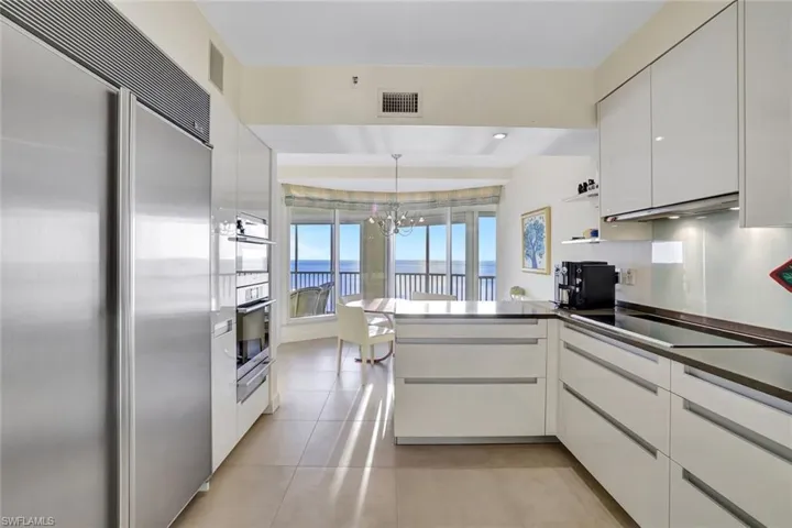 Kitchen with stainless steel appliances, a peninsula, white cabinets, and dark countertops