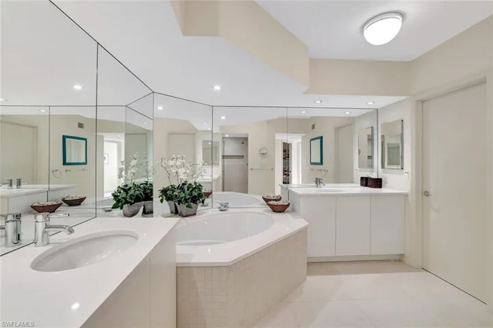 Full bathroom featuring a bath, light tile patterned floors, two vanities, and recessed lighting
