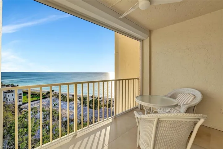 Balcony with view of water and beach and a ceiling fan