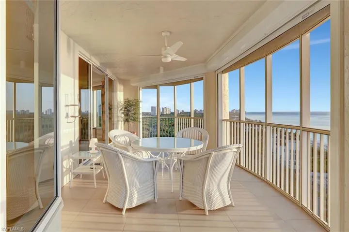Sunroom featuring ceiling fan, a water view, tile patterned floors, and outdoor dining space
