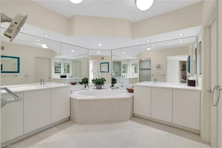 Full bathroom featuring a bath, light tile patterned flooring, recessed lighting, and two vanities