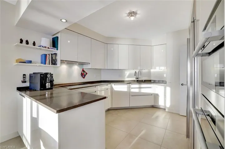 Kitchen featuring open shelves, a peninsula, double oven, modern cabinets, and white cabinets
