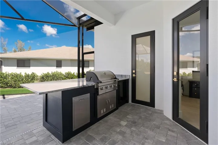 View of patio featuring area for grilling, a lanai, and a sunroom