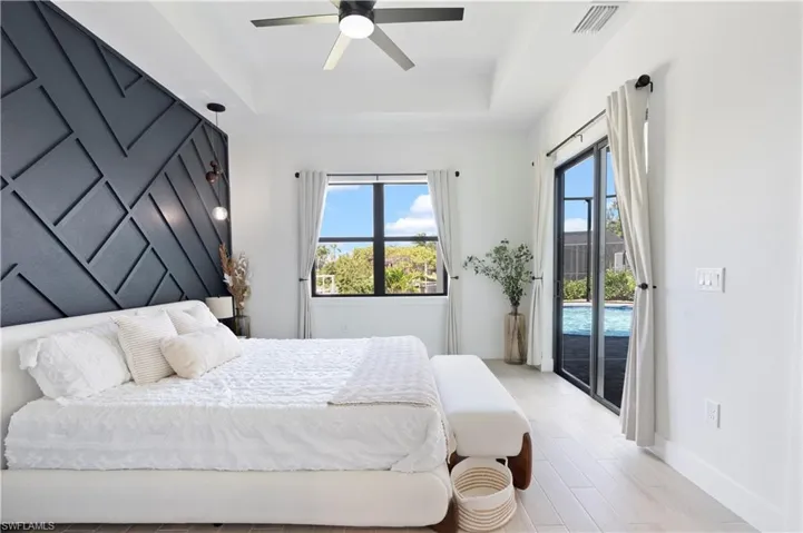 Bedroom featuring a tray ceiling, access to outside, ceiling fan, and light wood-type flooring