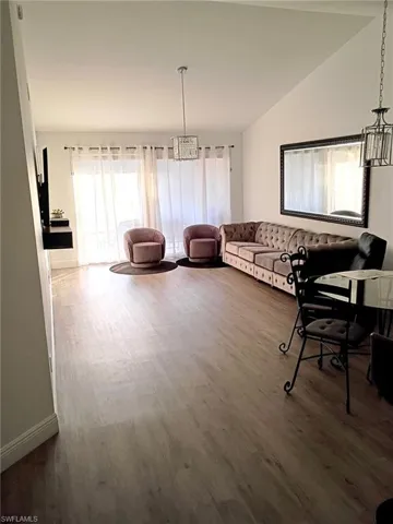 Living area featuring a chandelier, dark wood-style flooring, and lofted ceiling
